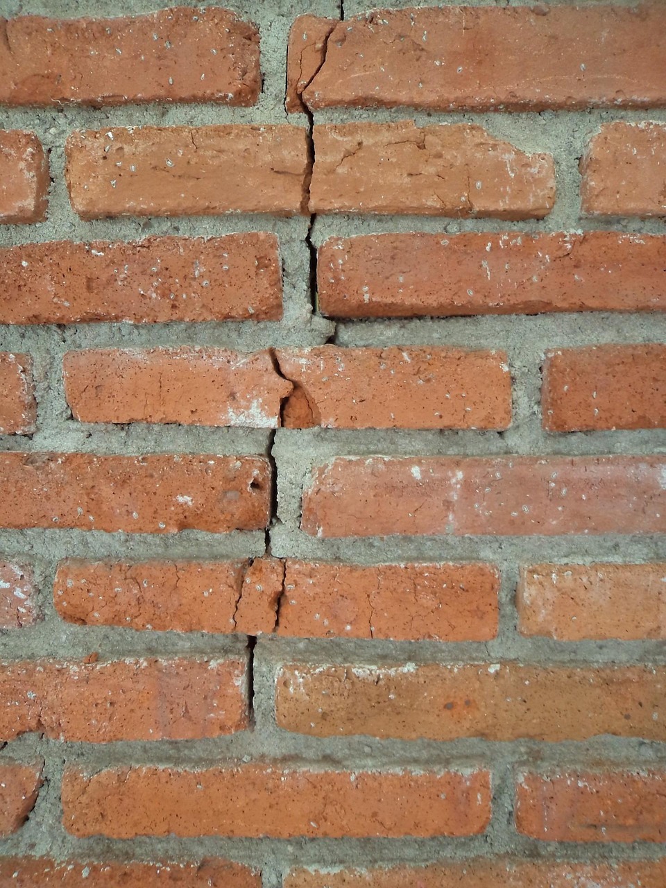 Trapsgewijze scheur die door stenen en voegen van een bakstenen buitenmuur loopt